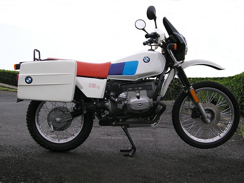 A white BMW R80 bike parked in a parking lot