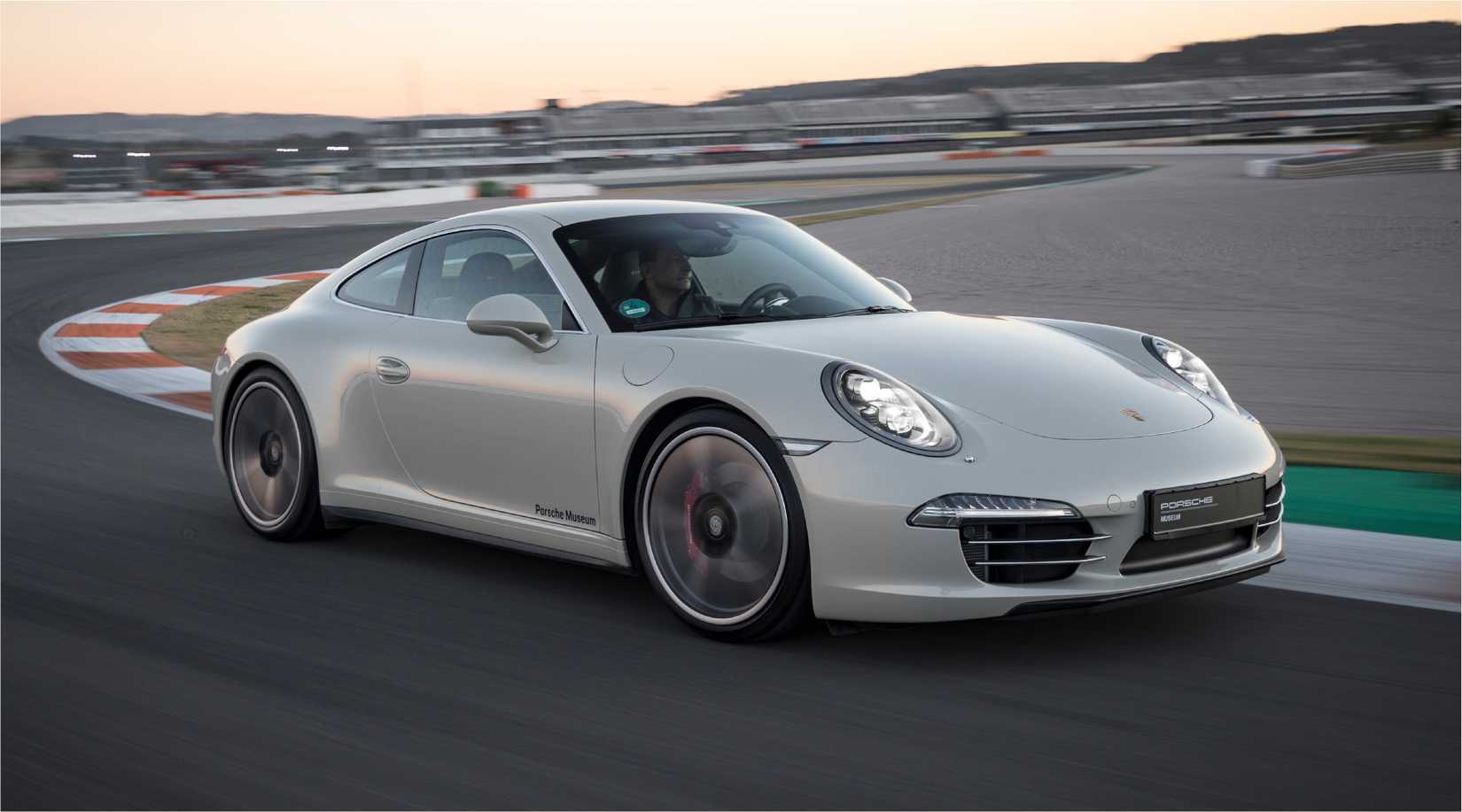 A front three-quarters shot of a white Porsche 911 991 driving on a racetrack.