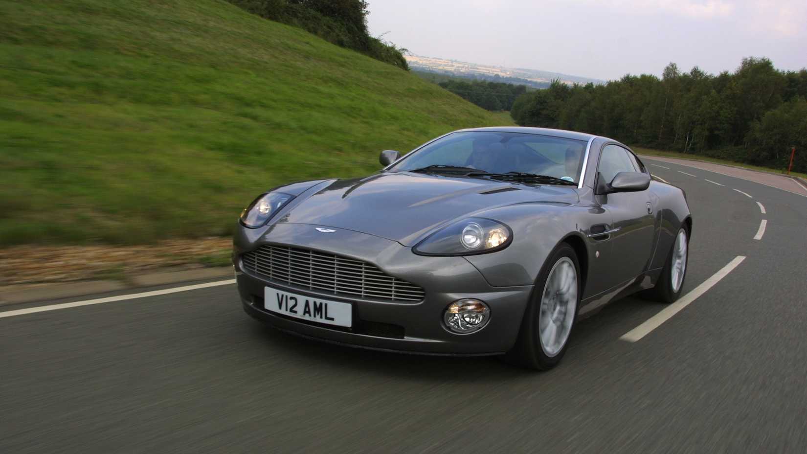 Front shot of a grey Aston Martin V12 Vanquish going down the road 
