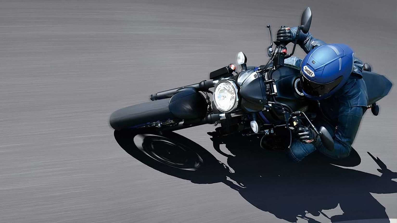 Foto frontal de um Suzuki SV650 preto fosco metálico 2023 inclinado em uma curva