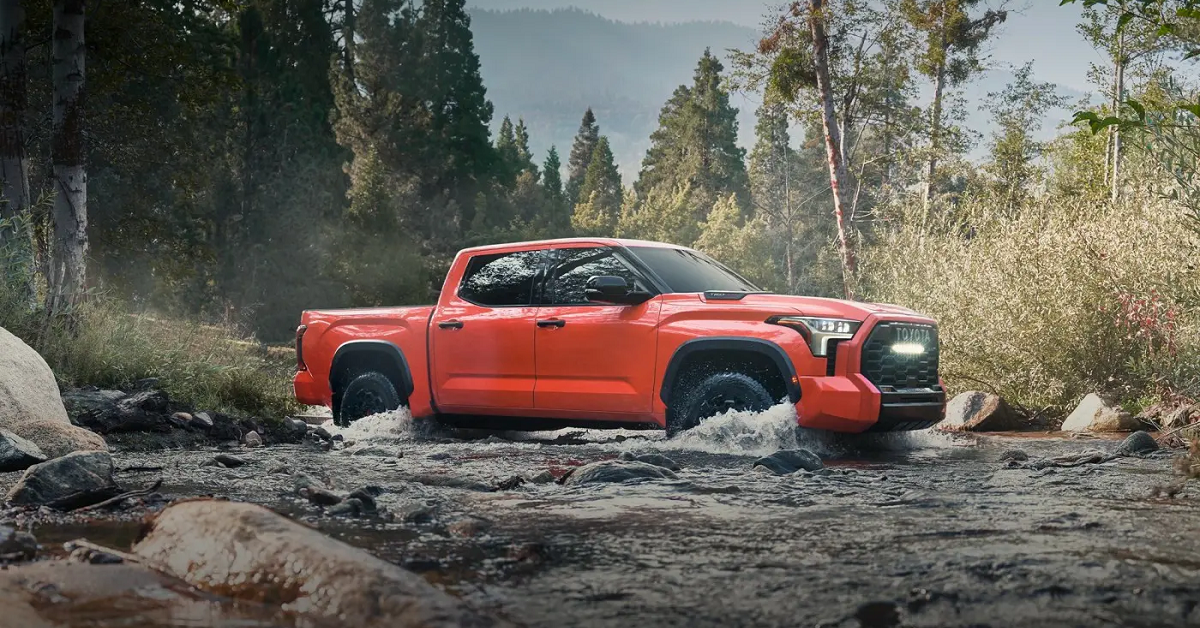 Vista lateral do passageiro de um Toyota Tundra TRD Pro CrewMax 2023 em off-road Solar Octane.