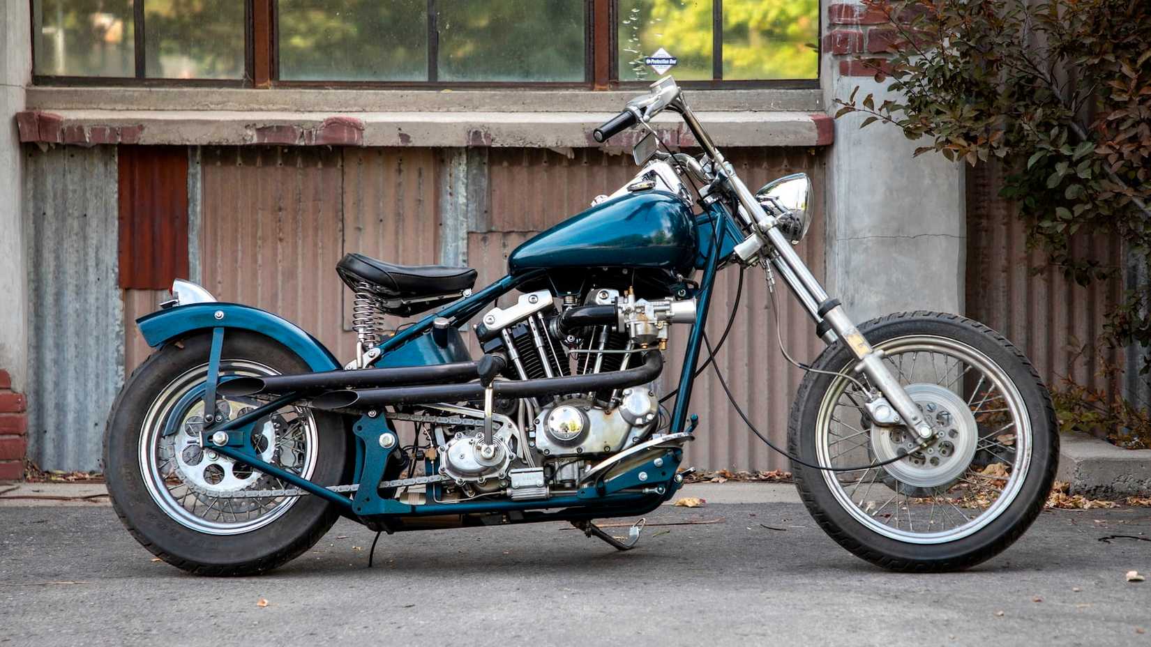 Custom blue Harley sportster bobber with short exhaust, aftermarket intake, and a chopped fender.
