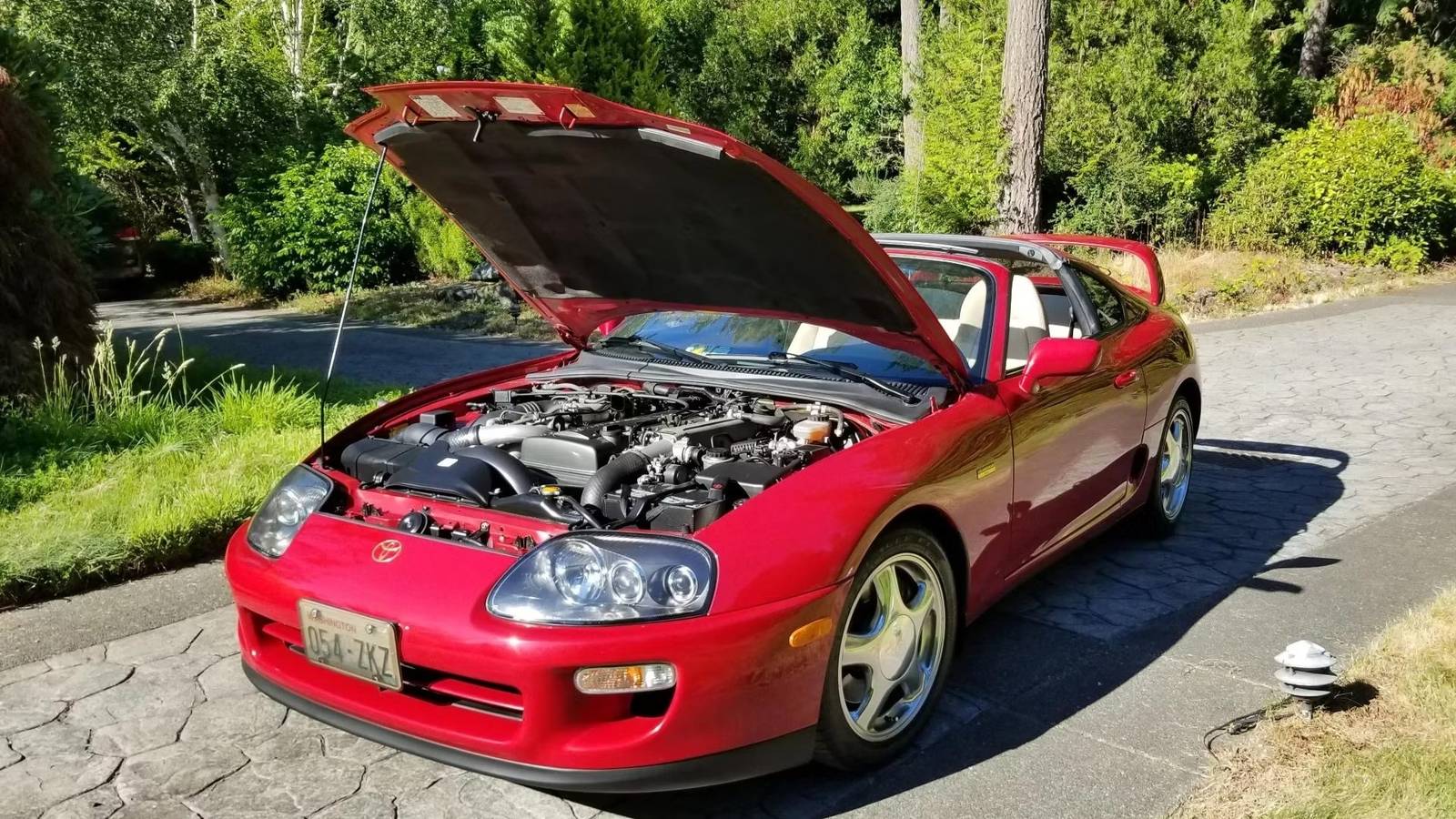 Un'auto con motore 2JZ-GTE aperto, con dettagli del motore visibili, in un parcheggio