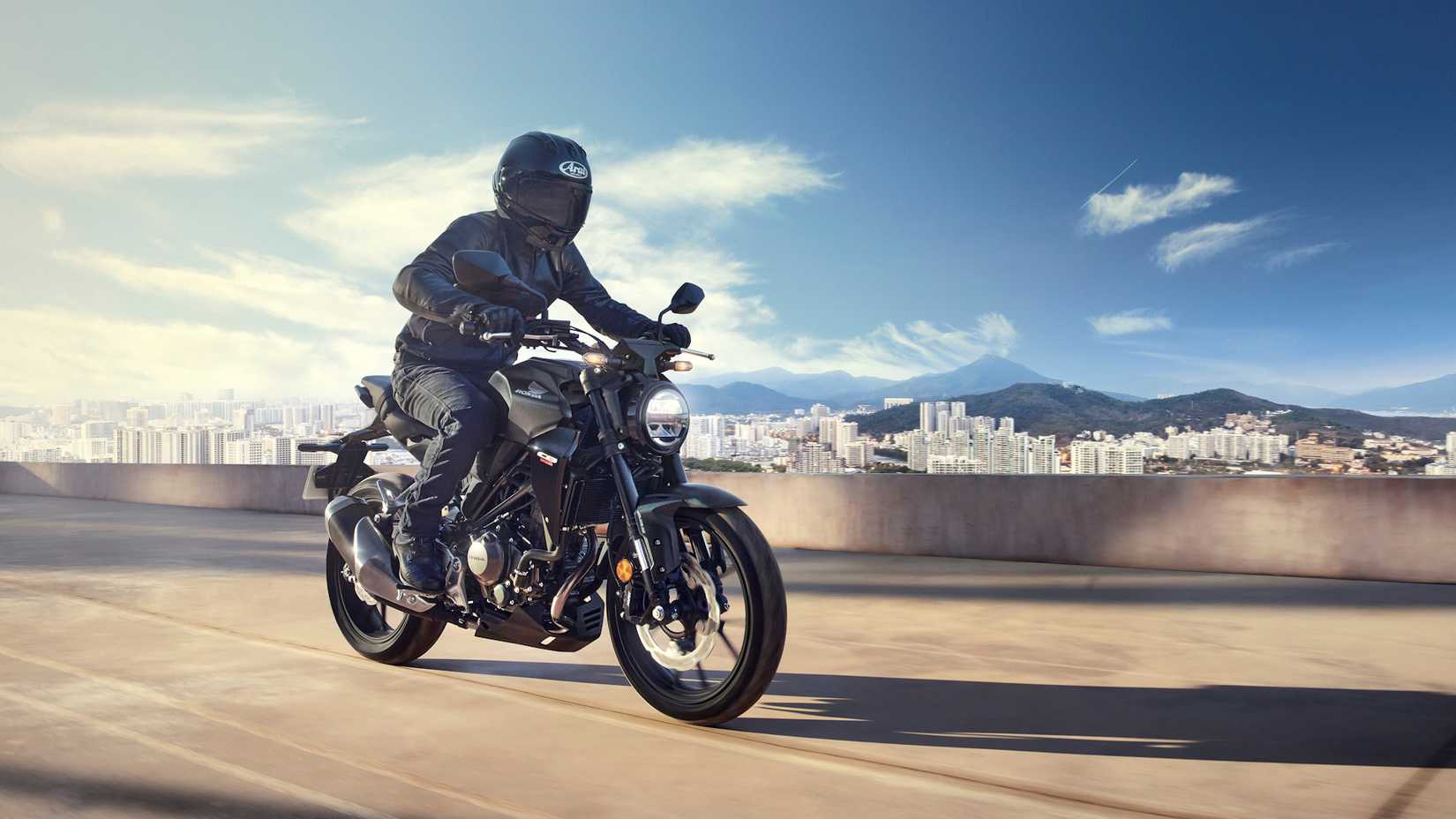 Honda CB300R preta 2022 na estrada em frente a uma paisagem urbana