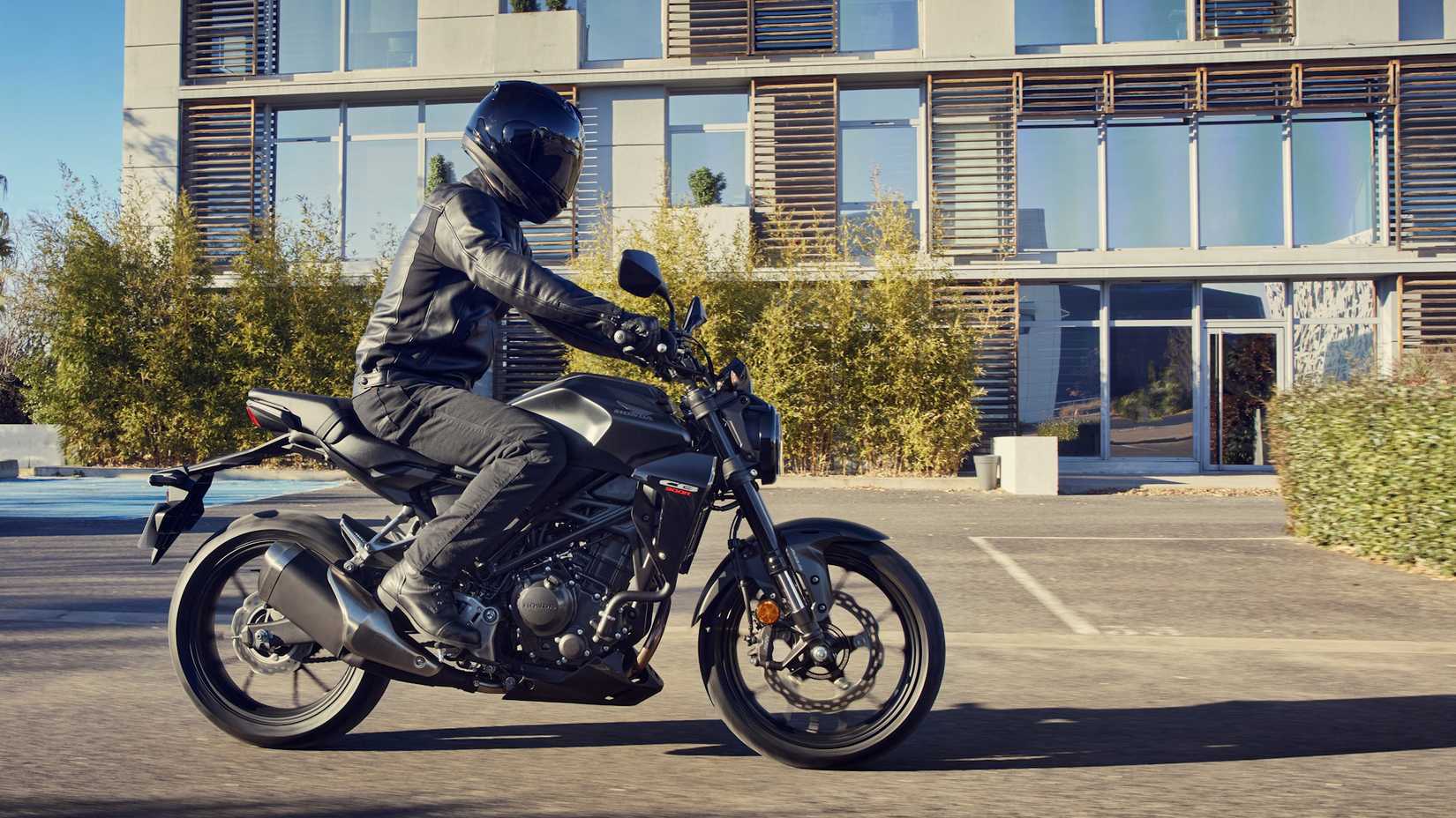 Honda CB300R preta passando por um estacionamento