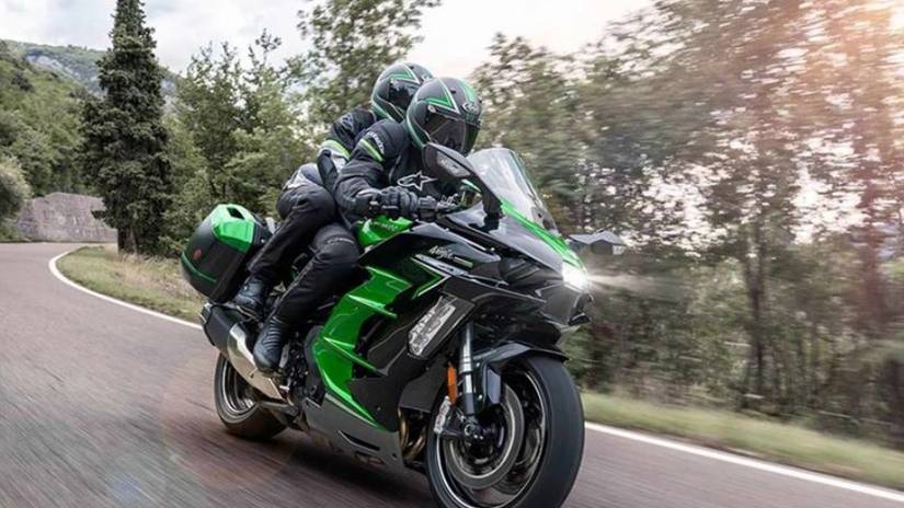 Uma Kawasaki H2 SX andando rápido em uma estrada de montanha com um passageiro