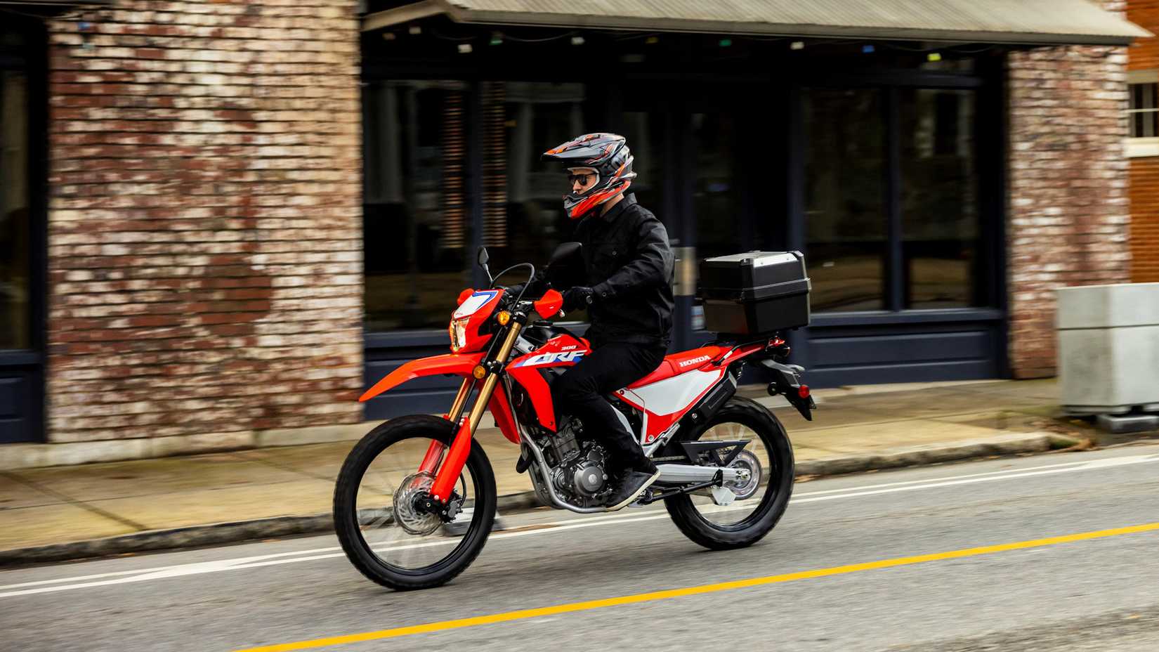 Honda CRF300L vermelha 2023 com acessórios cruzando a cidade