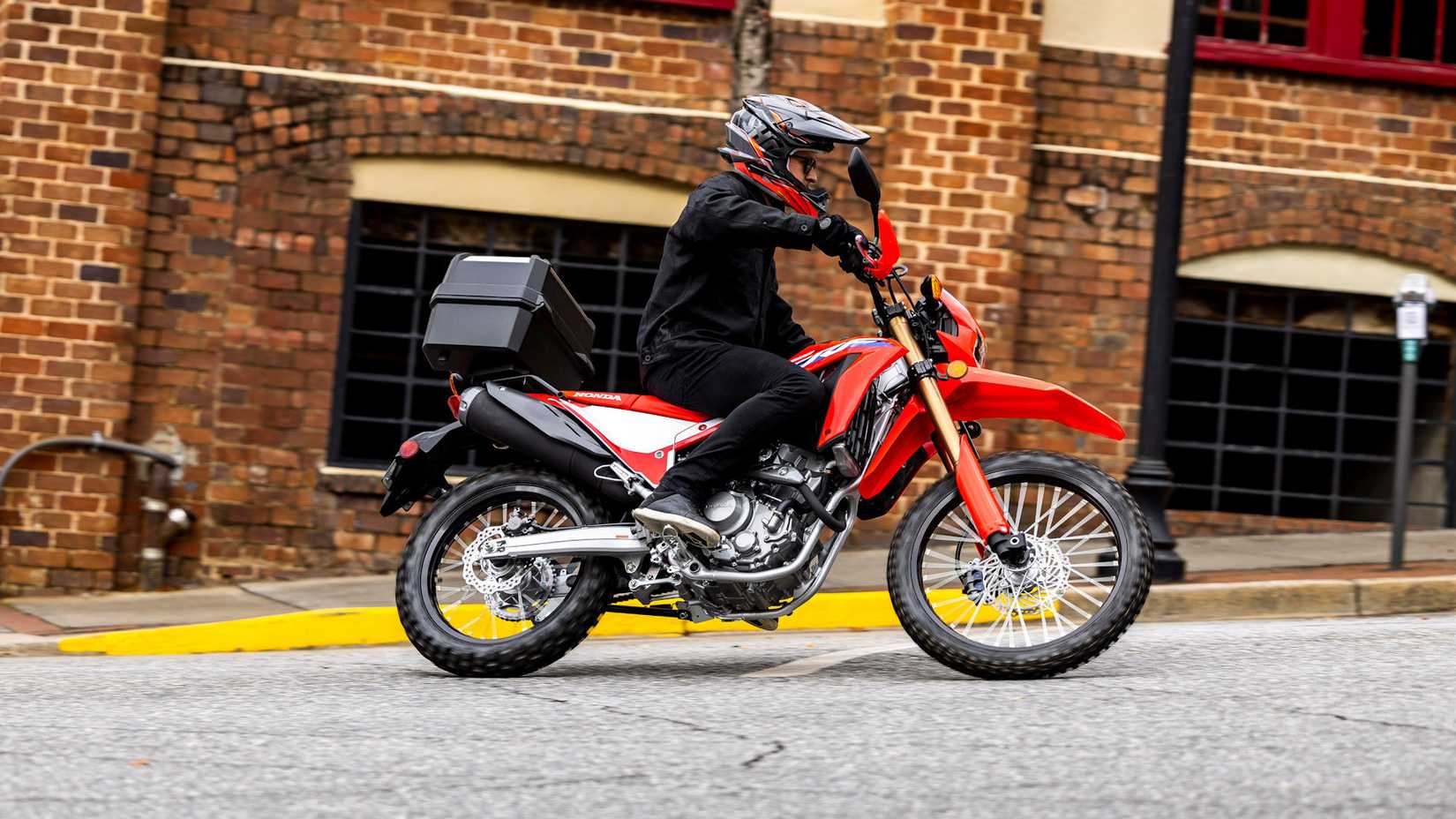 Accessorized red 2025 Honda CRF300L cruising through town