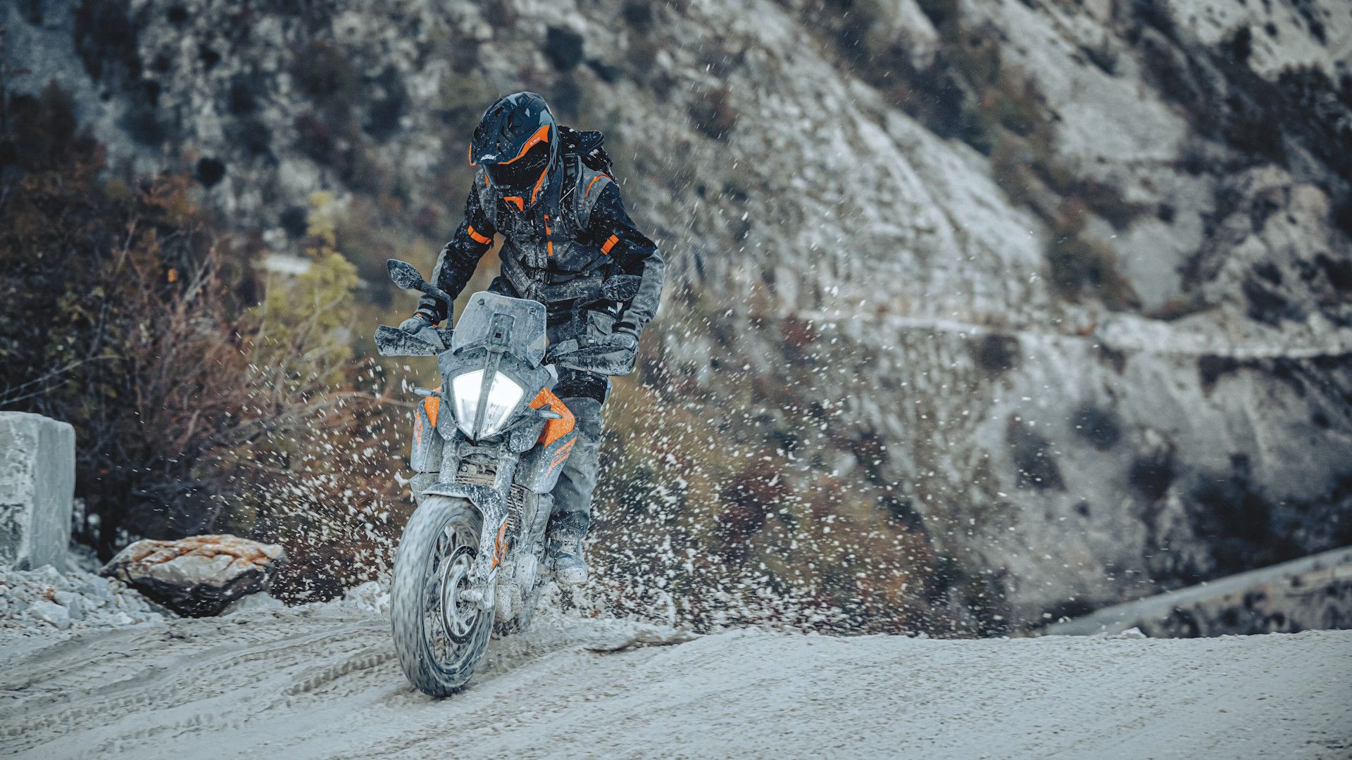 Orange 2023 KTM 390 Adventure tearing up a snowy trail
