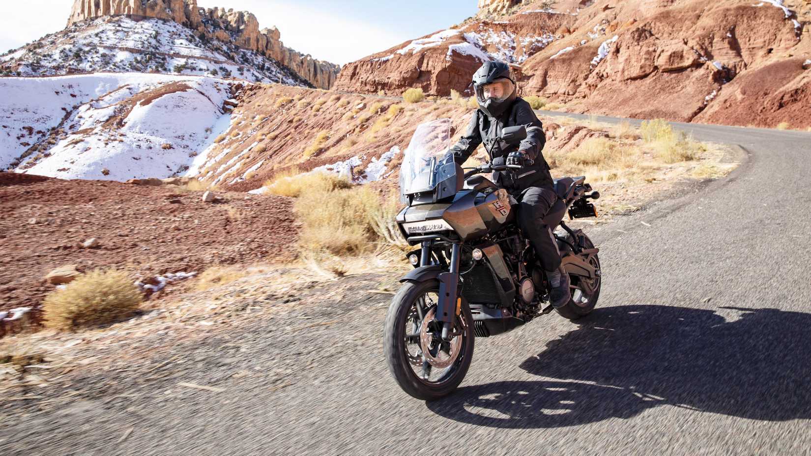 Black 2022 Harley-Davidson Pan America 1250 cruising on a rural road