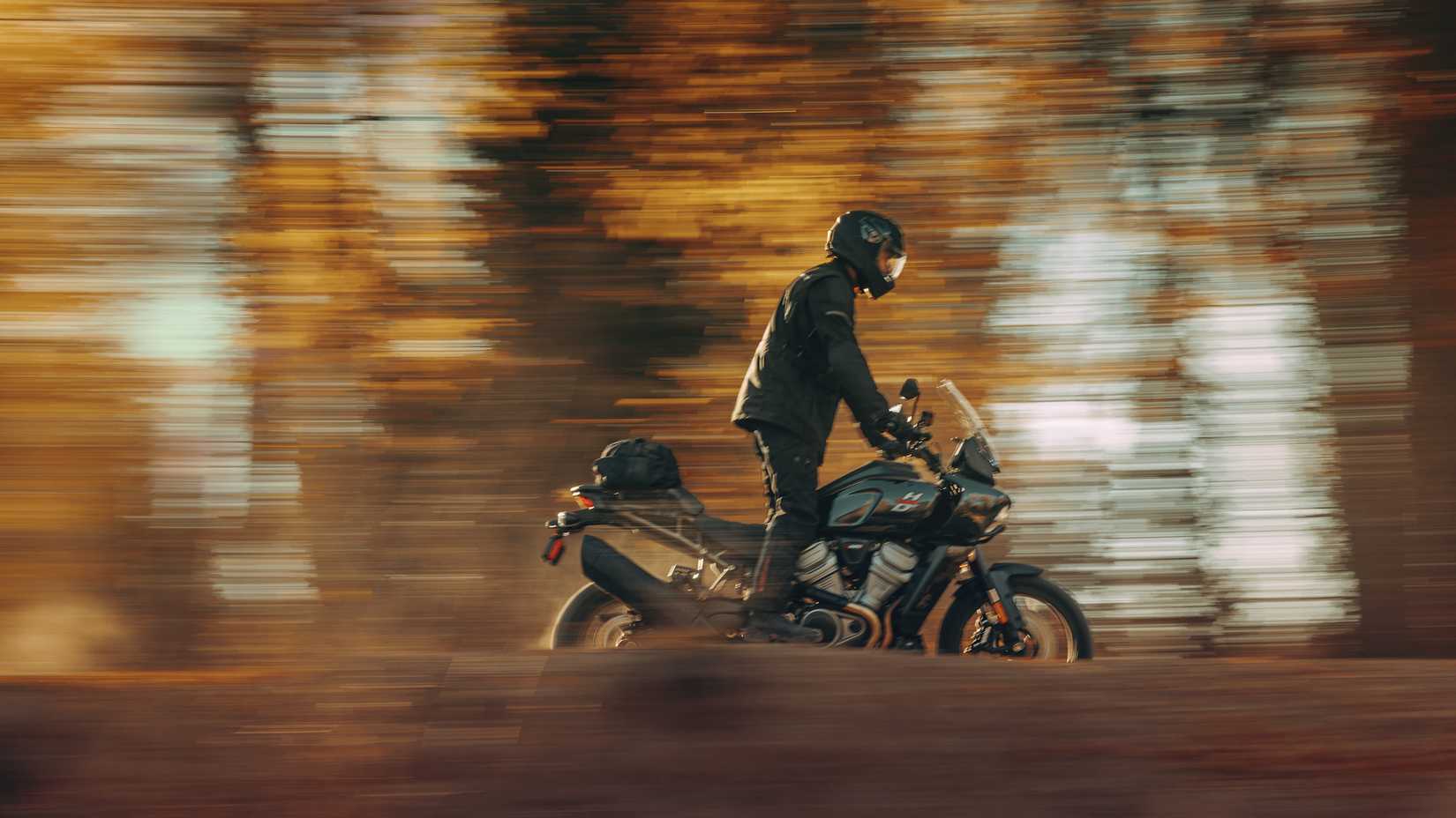 Black 2023 Harley-Davidson Pan America 1250 cruising through the woods