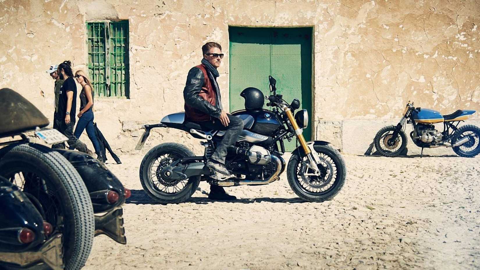 Piloto sentado montado em uma BMW R nineT preta 2017