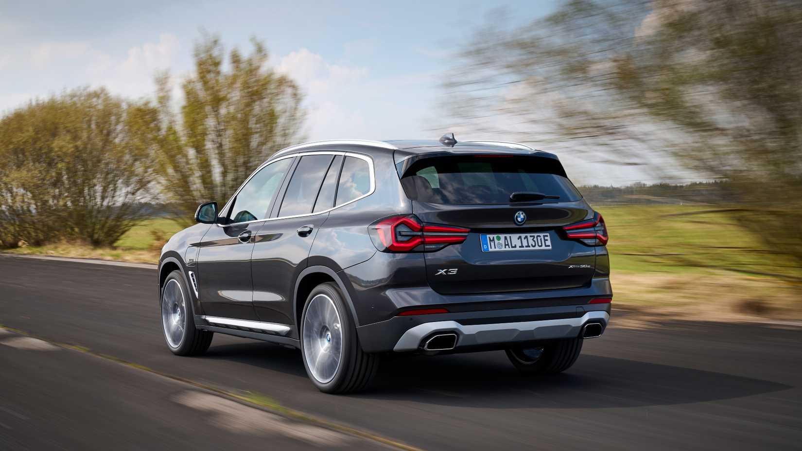 Rear 3/4 shot of a 2023 BMW X3 driving down the road