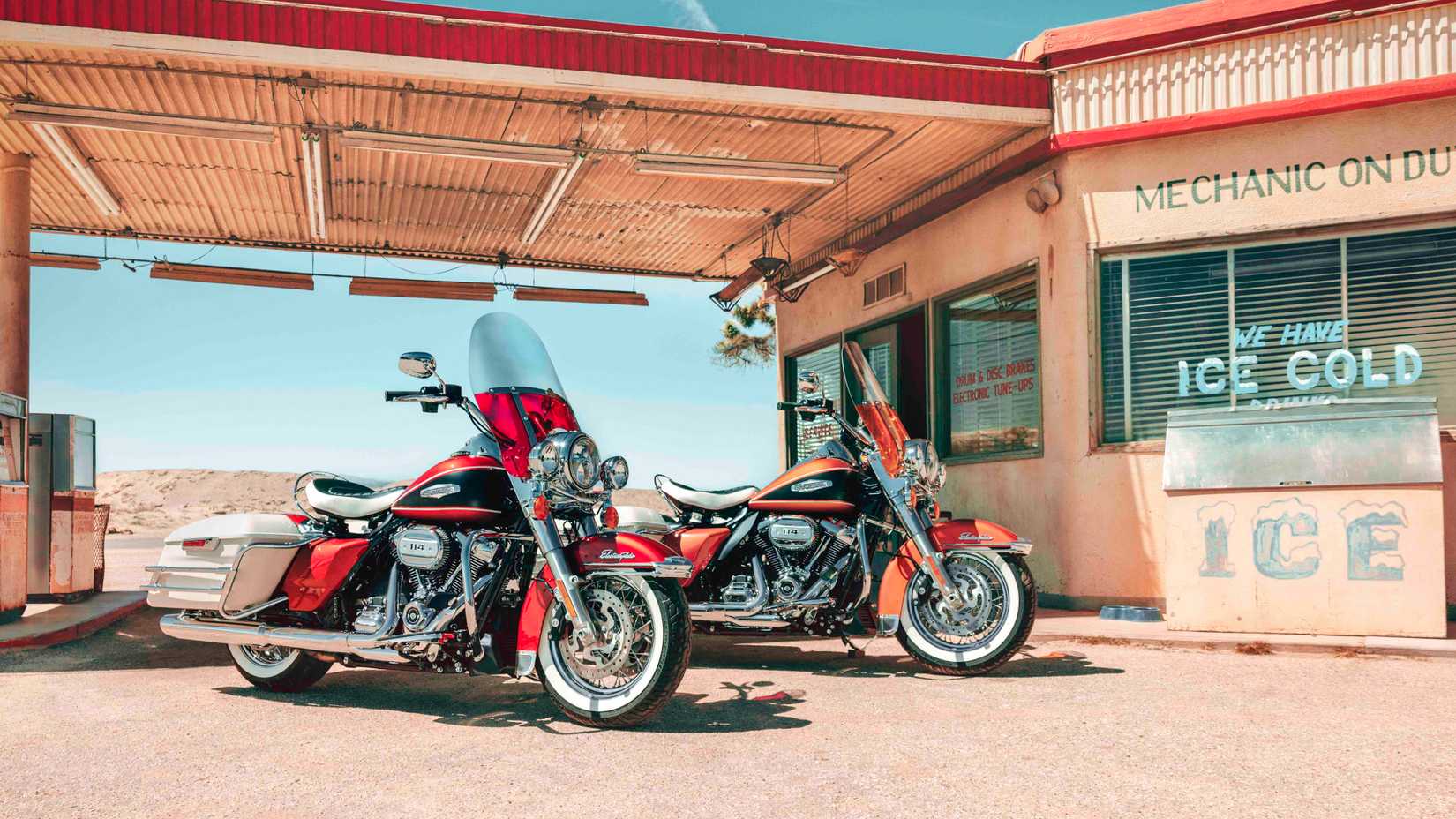 Two 2023 Harley-Davidson Electra Glide Highway King motorcycles parked outside a vintage gas station