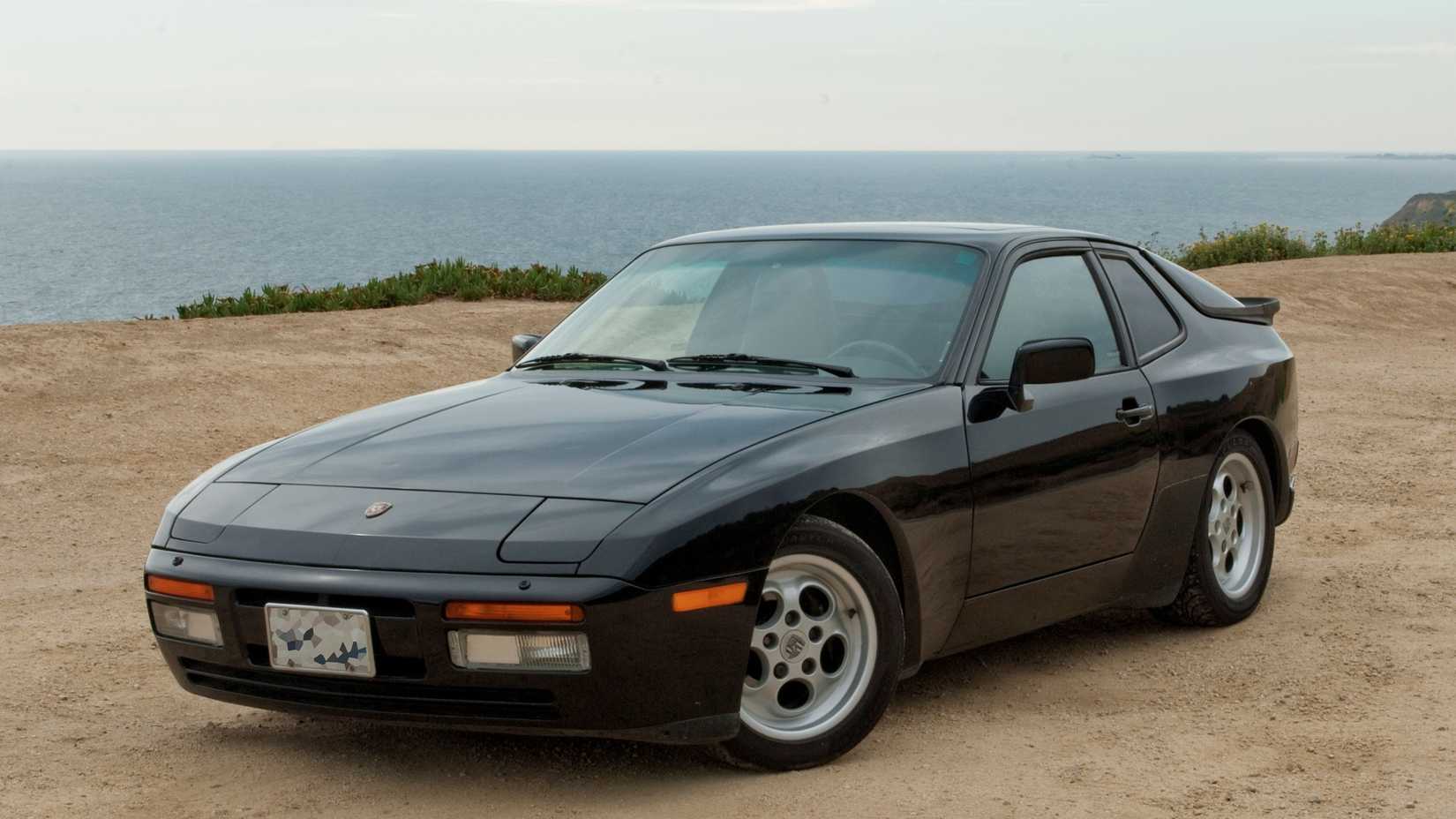 front 3/4 view of a black black 1986 Porsche 944 Turbo on a beach