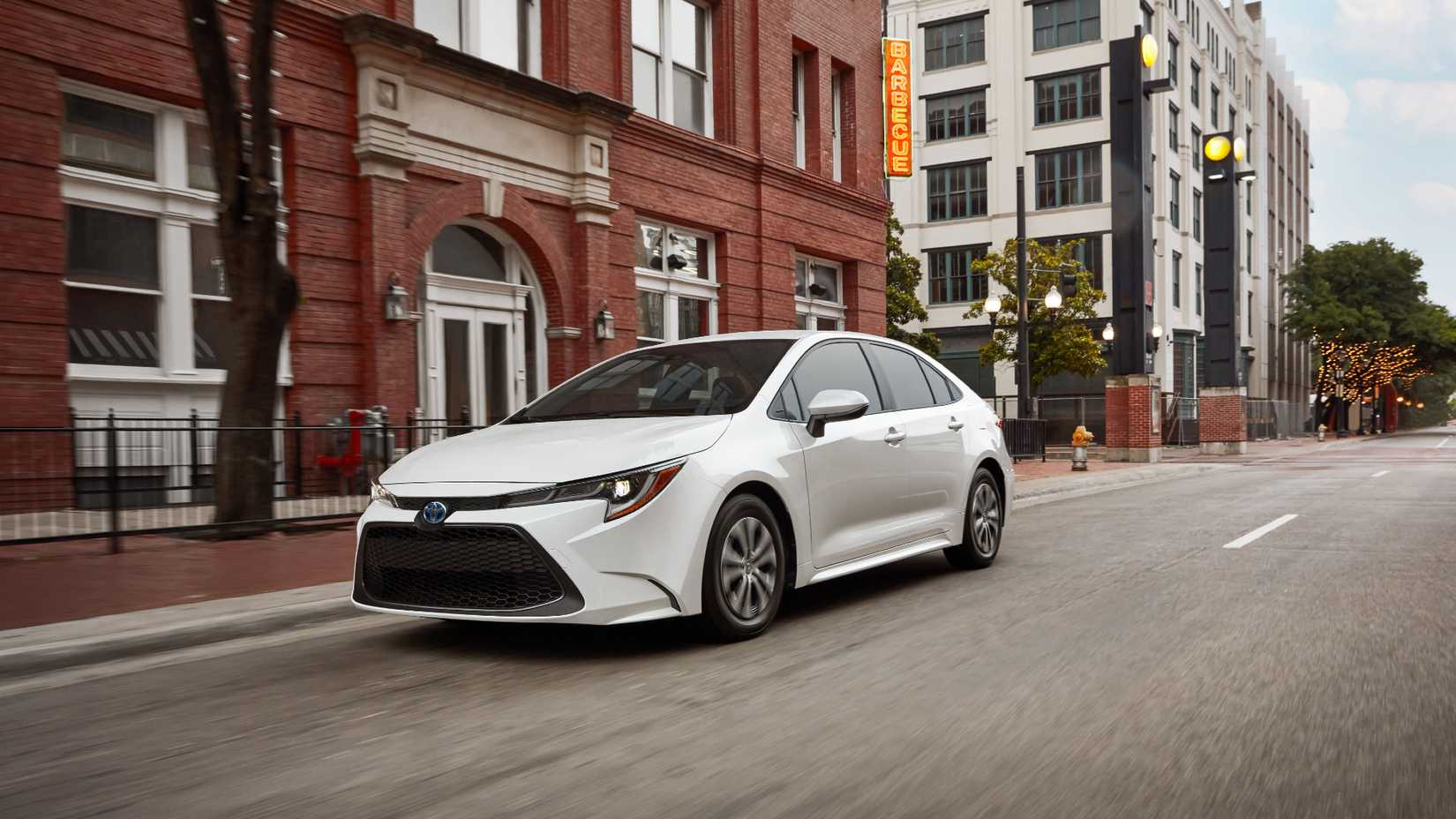 White 2022 Toyota Corolla Hybrid driving in a city