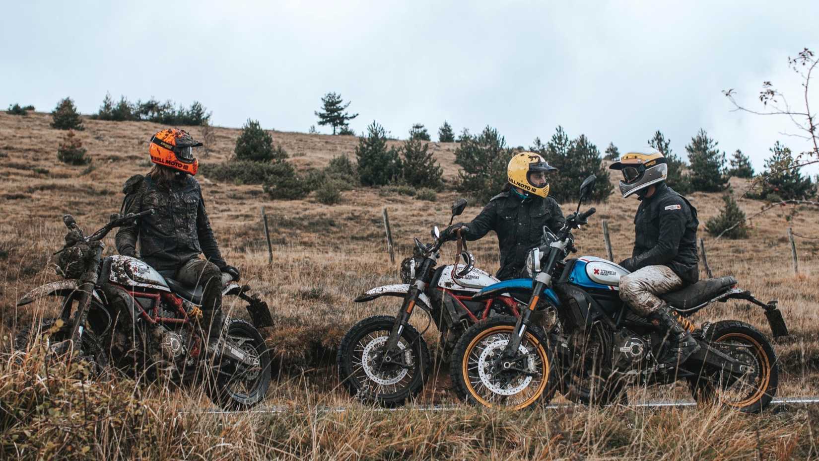 A trio of riders on Ducati Desert Sleds parked off-road