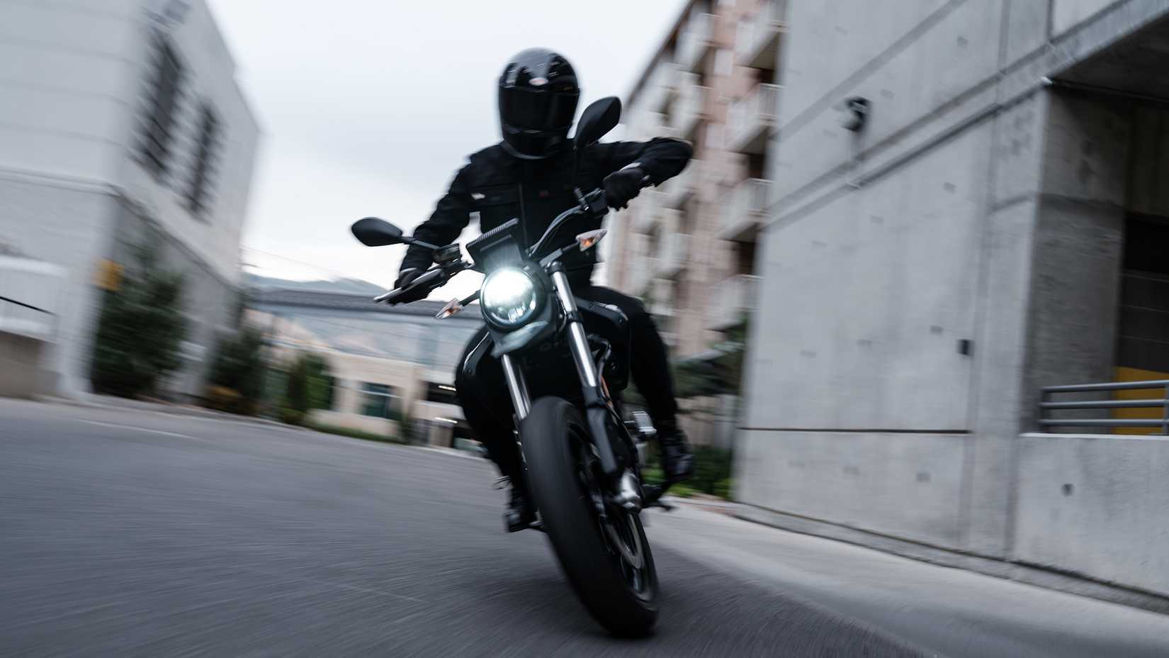 Foto frontal de um Jet Black 2023 Zero FXE cruzando a cidade