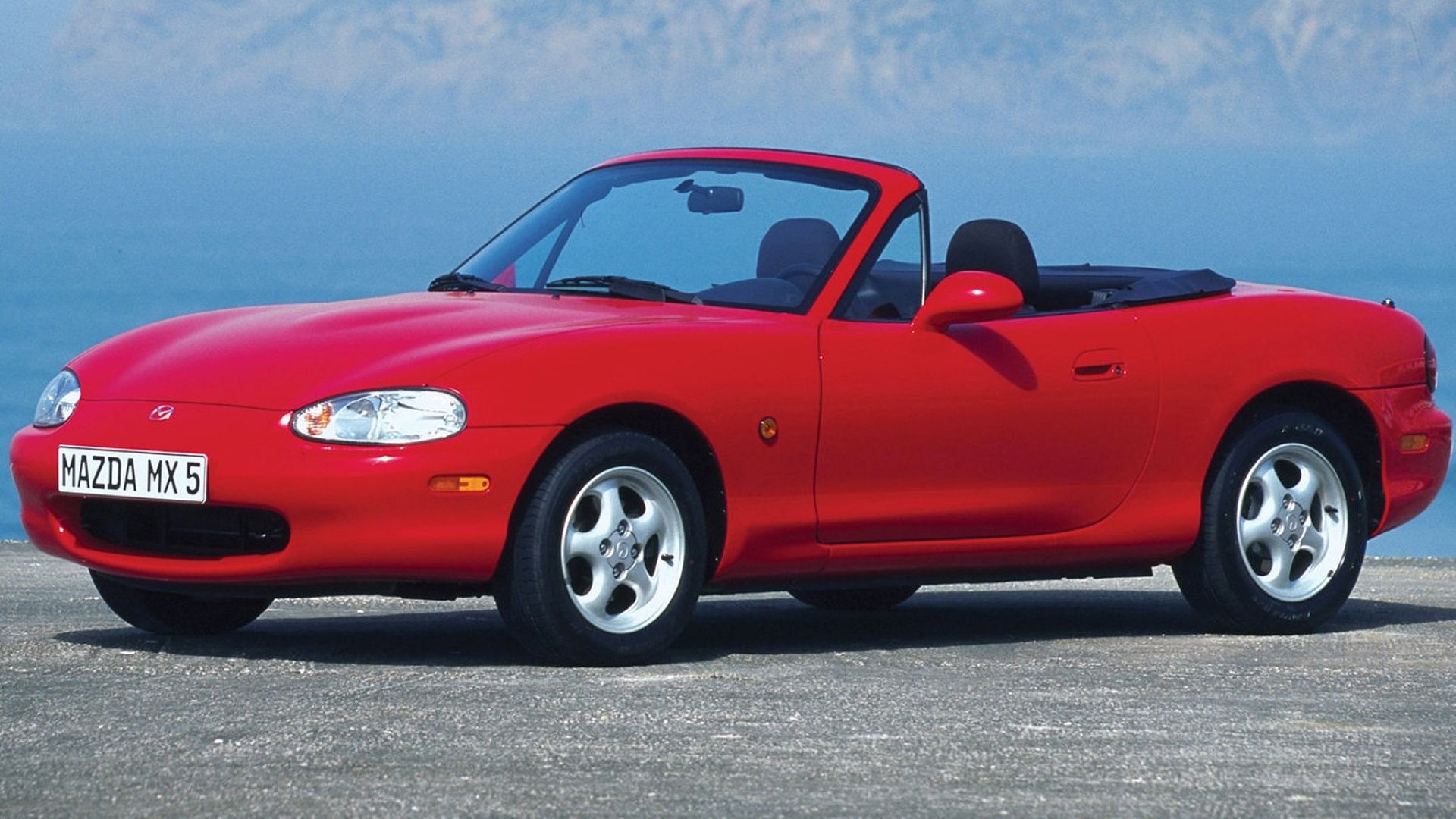 Side shot of a red 1998 Mazda MX-5 Miata parked