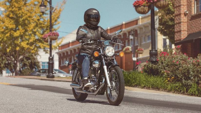 Piloto em uma Yamaha V-Star 250 andando por uma estrada urbana