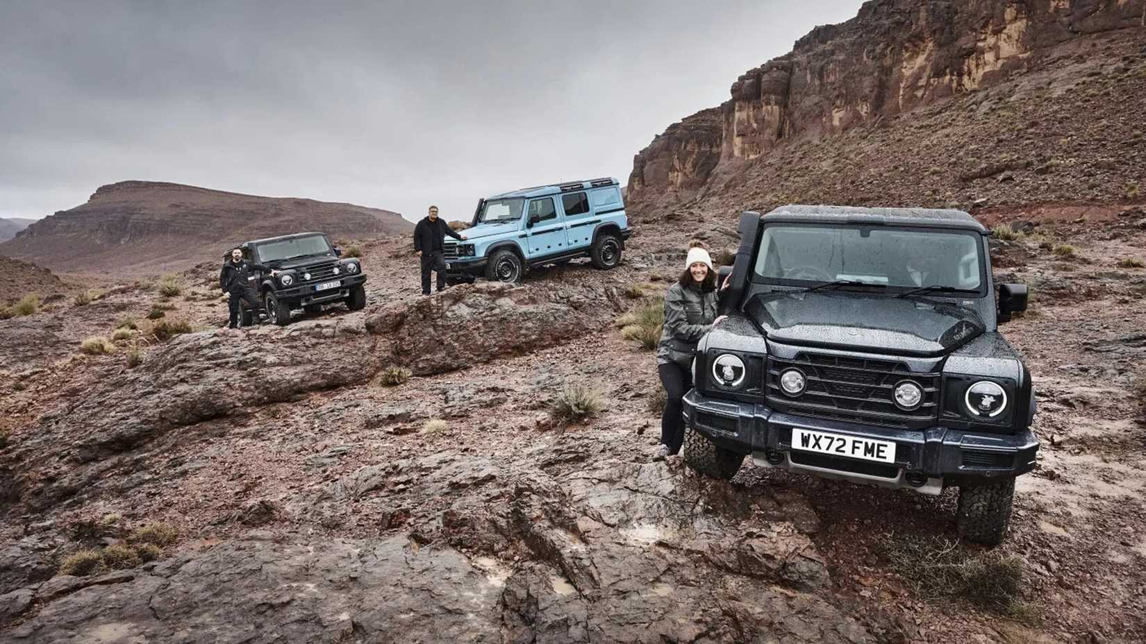 Three 2023 Ineos Grenadier SUVs on a rocky landscape, two black and one light blue