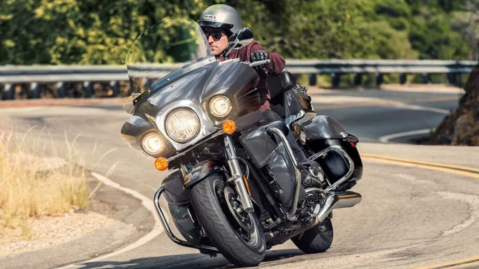 Um piloto enfrentando uma estrada sinuosa em uma Kawasaki Vulcan 1700 Voyager preta 2023