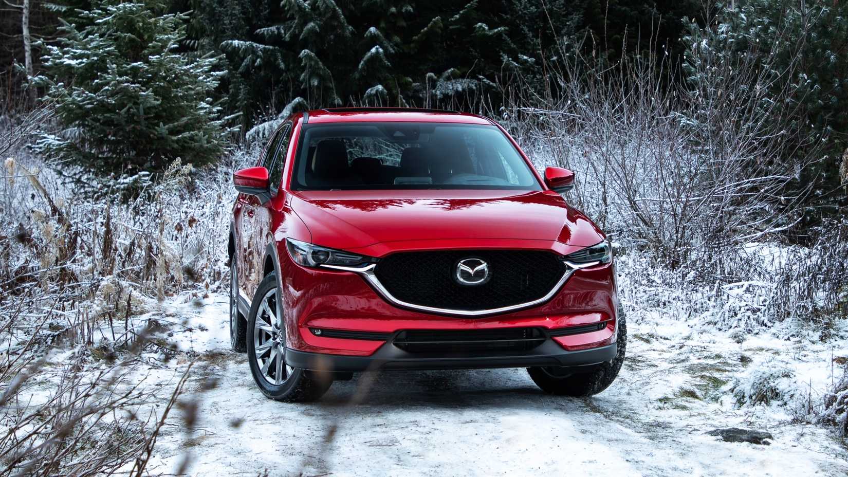 Foto frontal de um Mazda CX-5 2024 vermelho estacionado na neve
