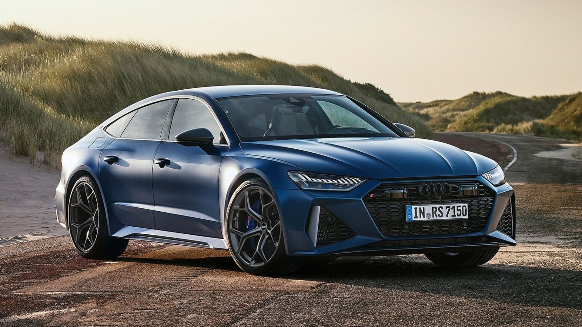 Vista de três quartos do Audi RS7 Sportback Performance 2023 estacionado em frente às dunas de areia
