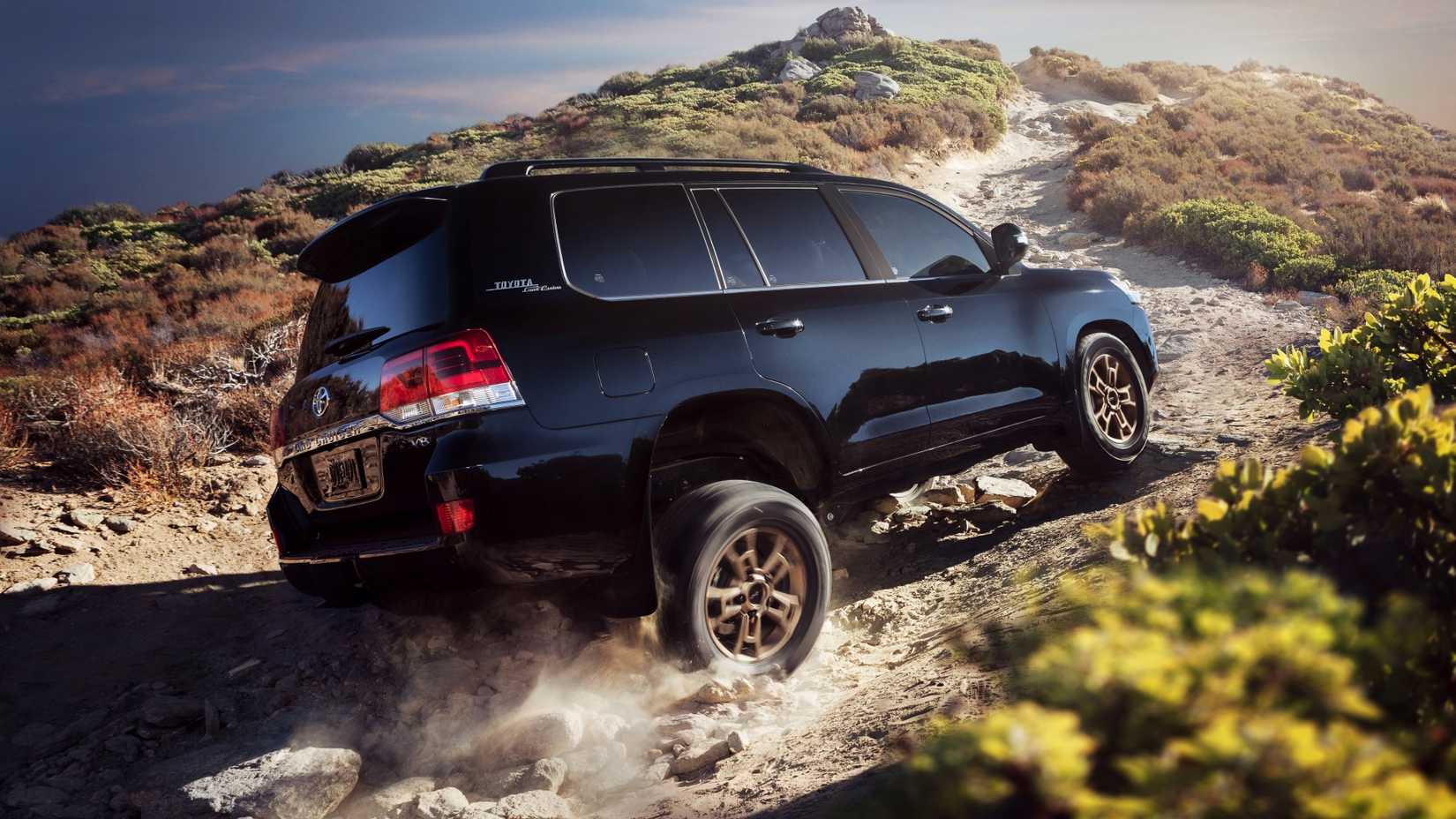 Rear 3/4 shot of the 2021 Land Cruiser kicking up some dirt
