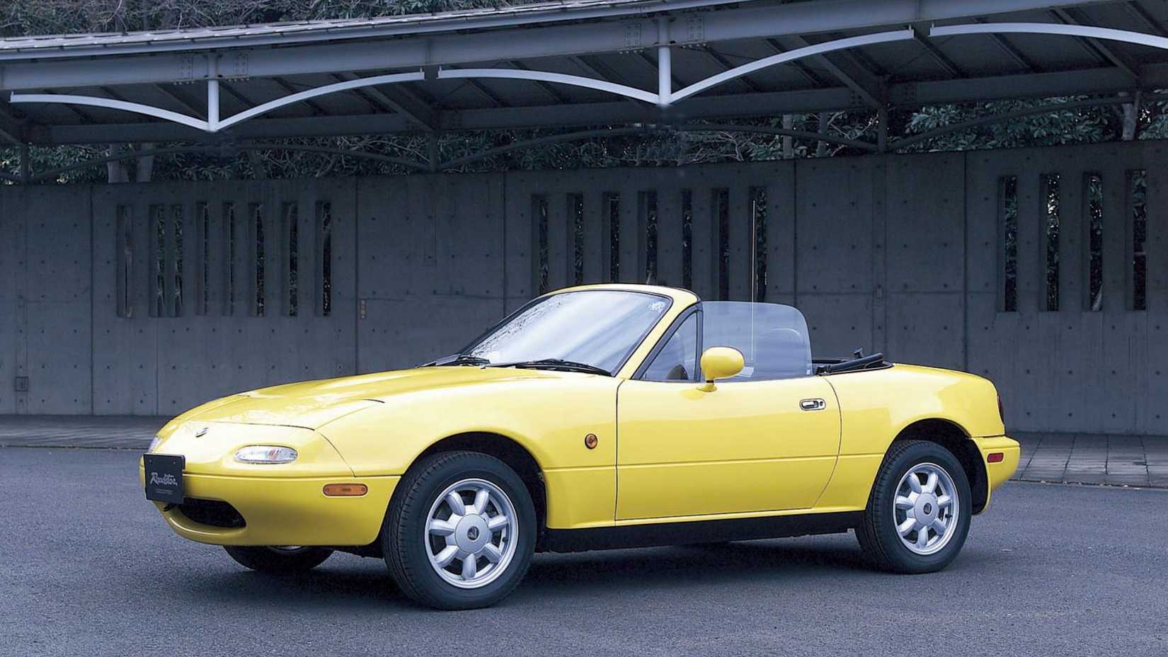 Mazda MX-5 Miata NA in yellow parked in front of building
