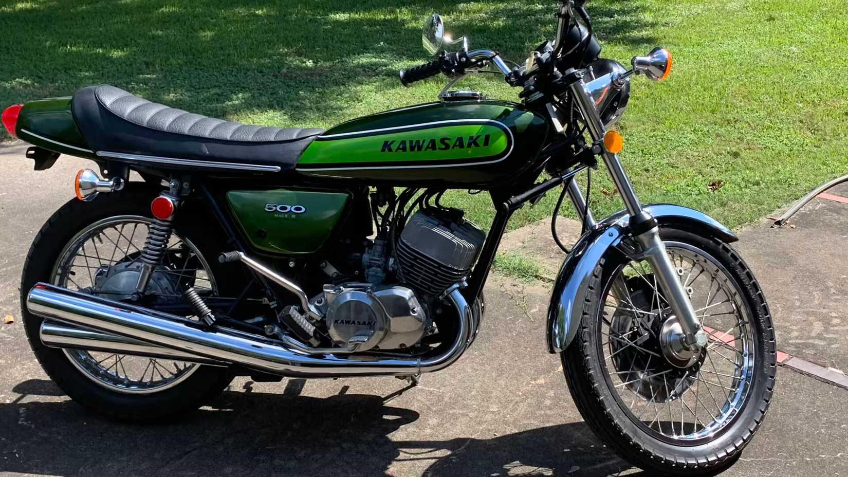 Side standing shot of a green Kawasaki H1 Mach III with outdoor background.