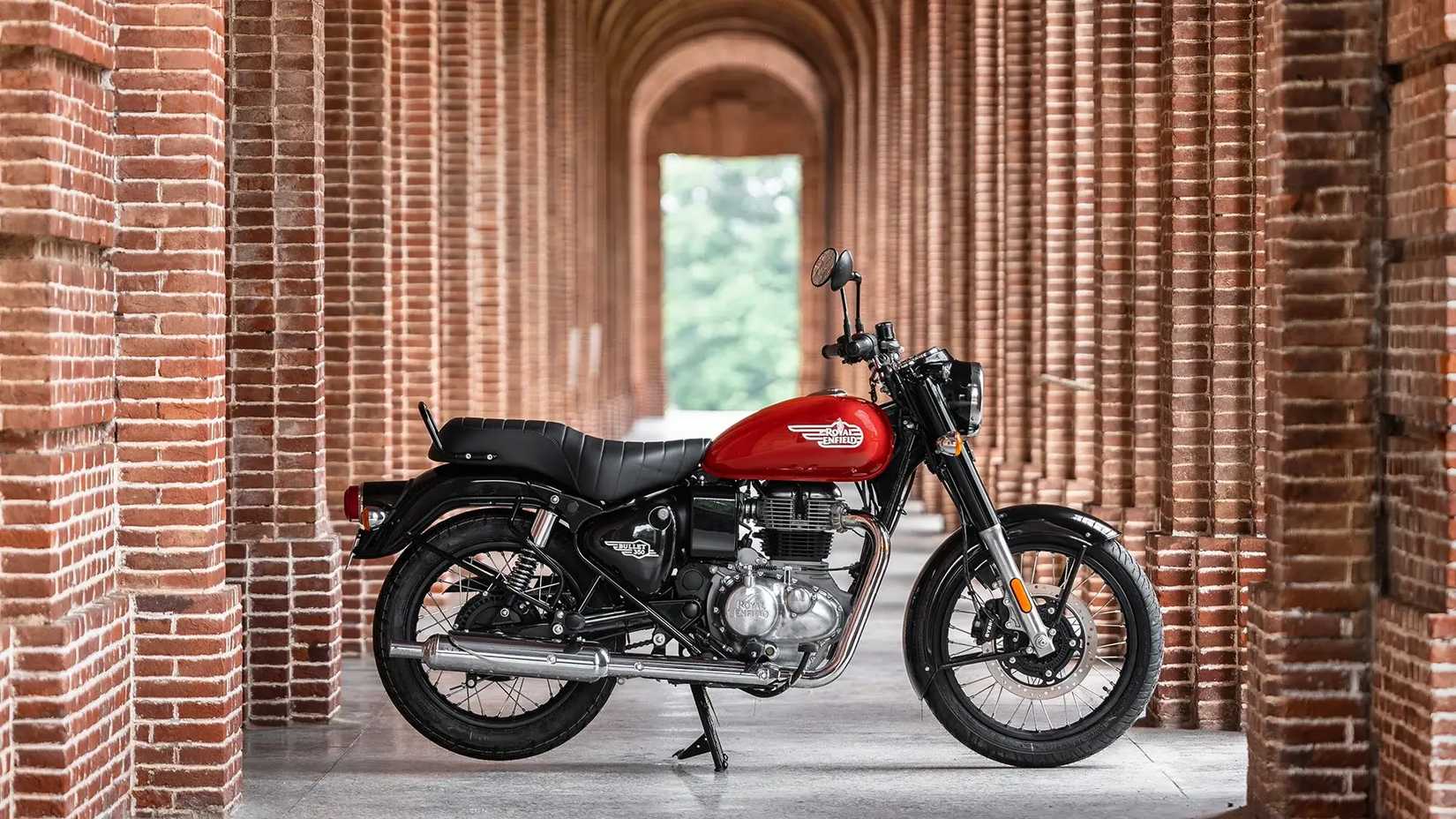 Right side statue shot of the Royal Enfield Bullet 350 with red/black paint on the main stand in between several arches
