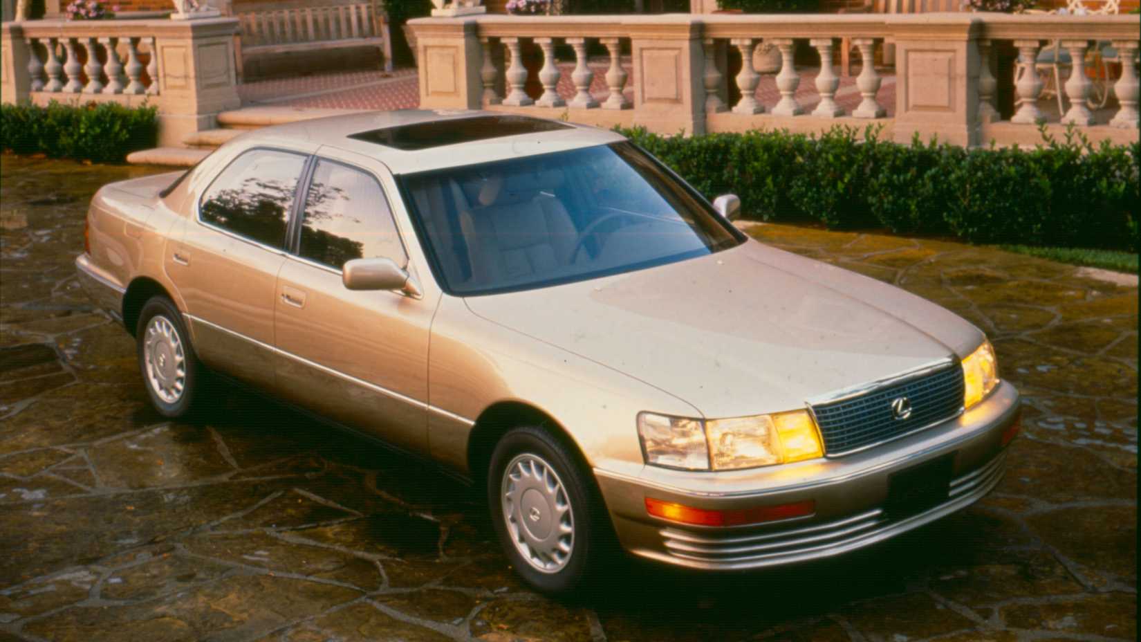 Aerial front three-quarter shot of a gold first gen Lexus LS400
