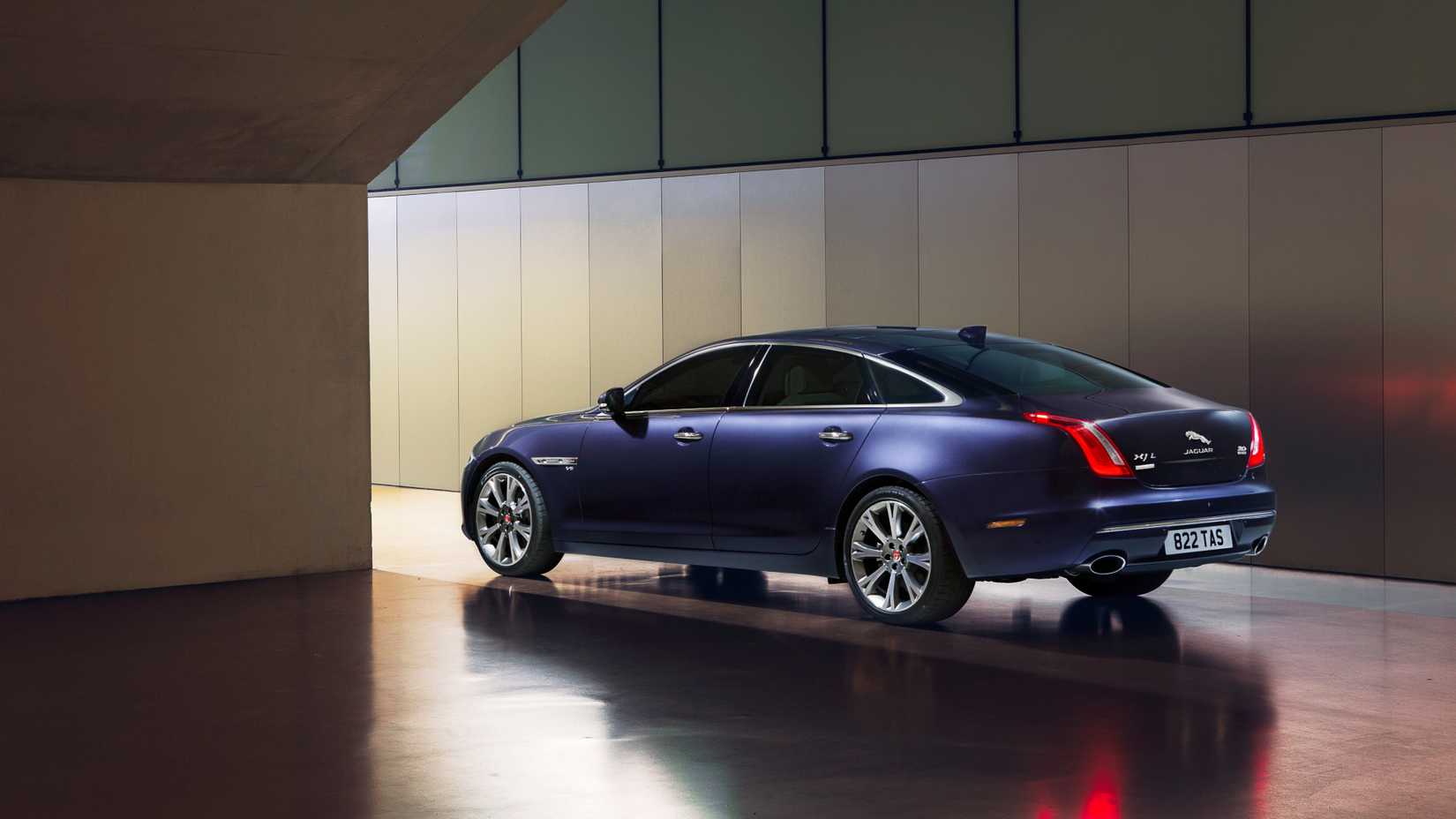 Foto traseira 3/4 de um Jaguar XJ 2013 em azul estacionado em um prédio