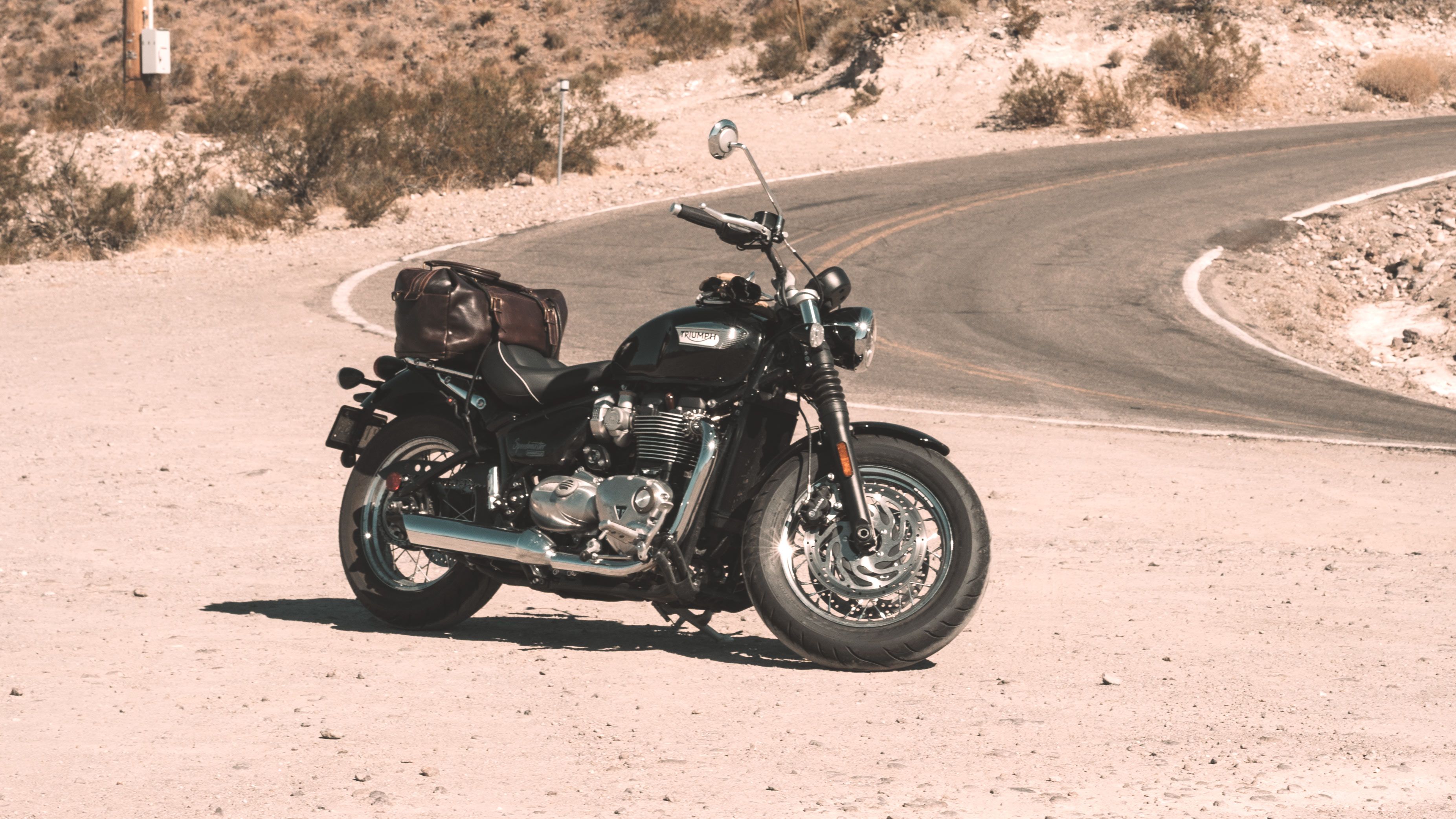 A 2023 Triumph Bonneville Speedmaster parked in front of a winding bend road.