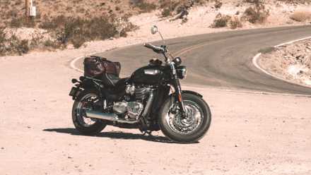 Uma Triumph Bonneville Speedmaster 2023 estacionada em frente a uma estrada sinuosa.