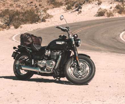 Uma Triumph Bonneville Speedmaster 2023 estacionada em frente a uma estrada sinuosa.