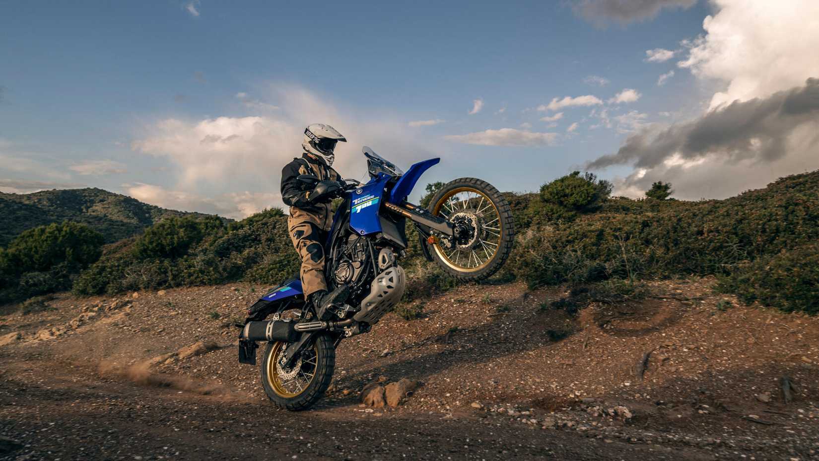 A 2023 Yamaha Tenere 700 Extreme pulling a wheelie on an off-road trail