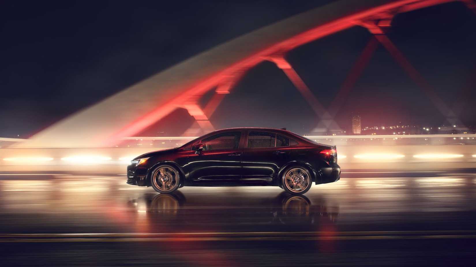 2024 Toyota Corolla Hybrid Nightshade driving over an illuminated bridge at night