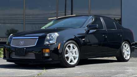Cadillac CTS-V 2004 em preto posando em frente a um prédio de escritórios