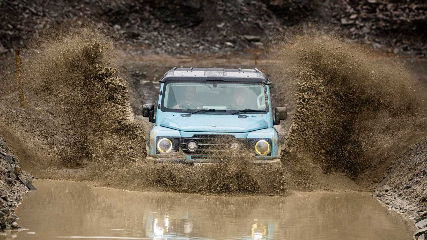 INEOS Grenadier in blue driving through deep muddy puddle