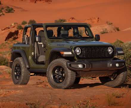 Uma foto frontal de três quartos de um Jeep Wrangler 2024 verde exército posando em um deserto