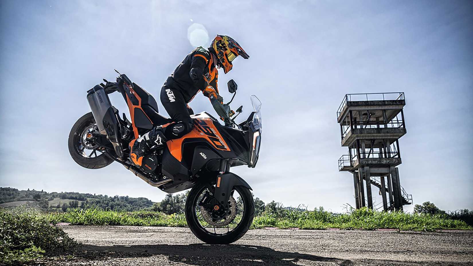 Action side-profile photograph of 2023 KTM 1290 SUPER ADVENTURE S rider performing a stoppie/endo stunt on the front tire.