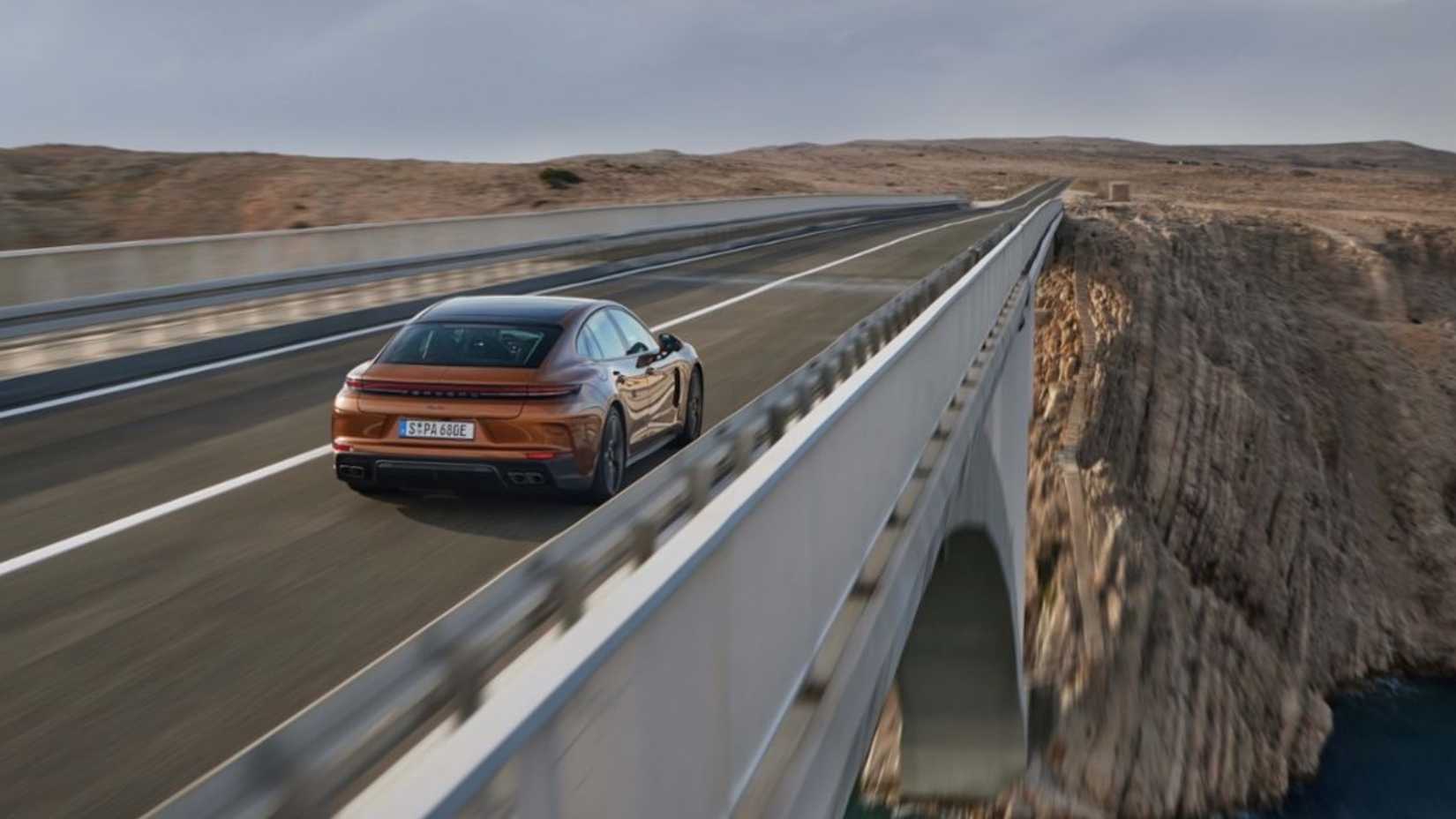 2024 Porsche Panamera Turbo E-Hybrid em ouro posando na ponte sobre o rio