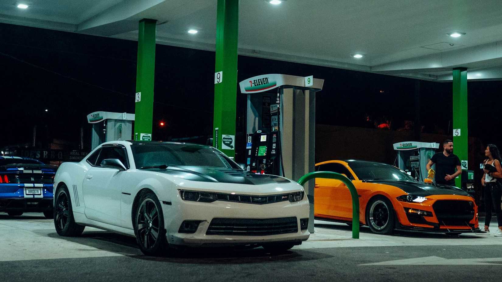 Ford Mustang and Cheverolet Camaro Muscle Cars At A Gas Station Night
