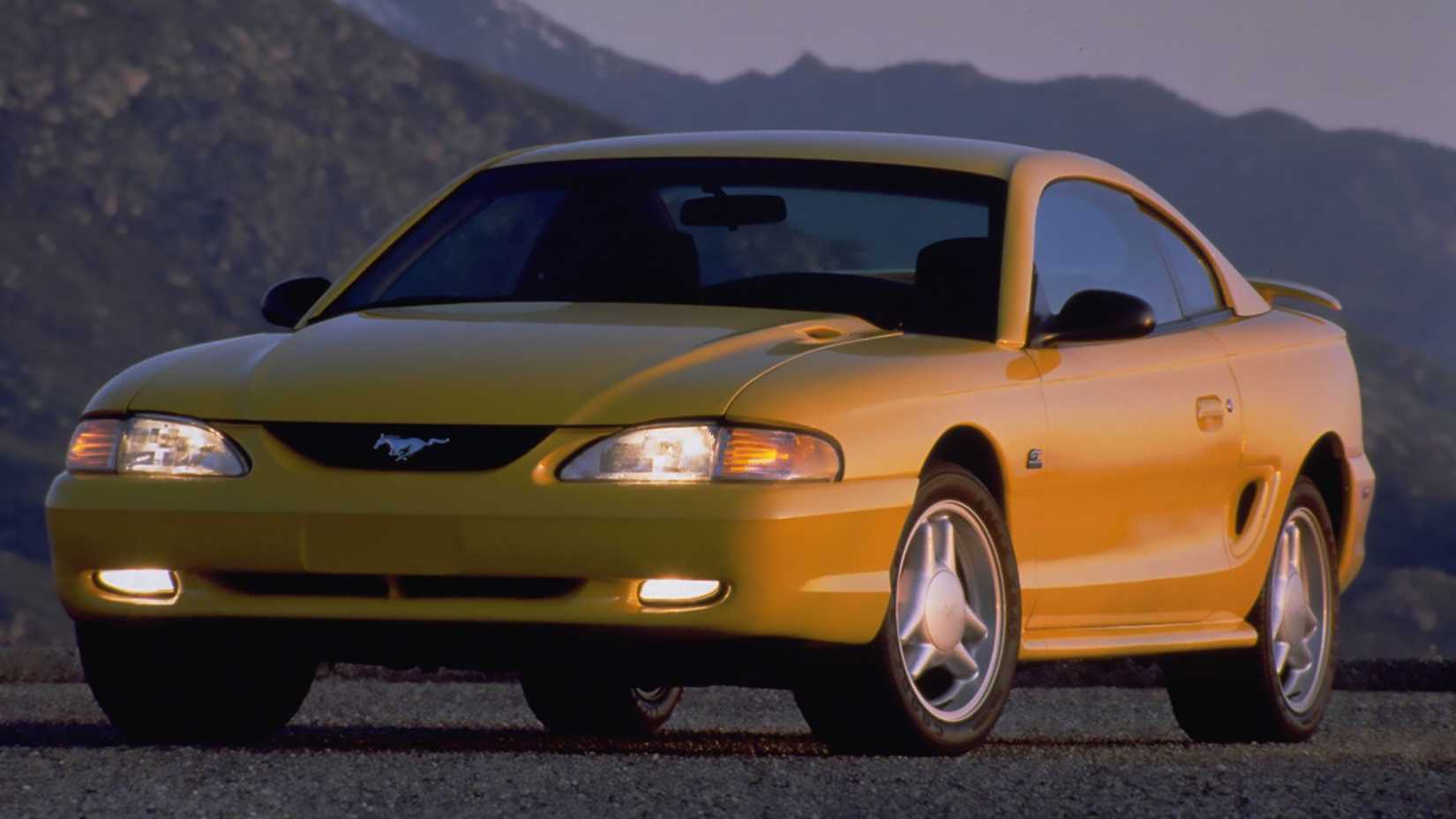 A side shot of a yellow 1994 Ford Mustang SVT Cobra parked on the tarmac