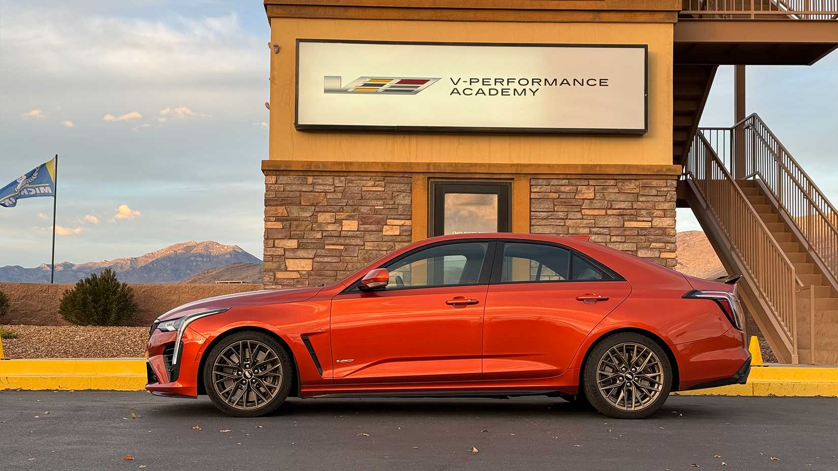 2023 orange Cadillac CT4-V Blackwing side shot parked in front of V-Performance Academy sign