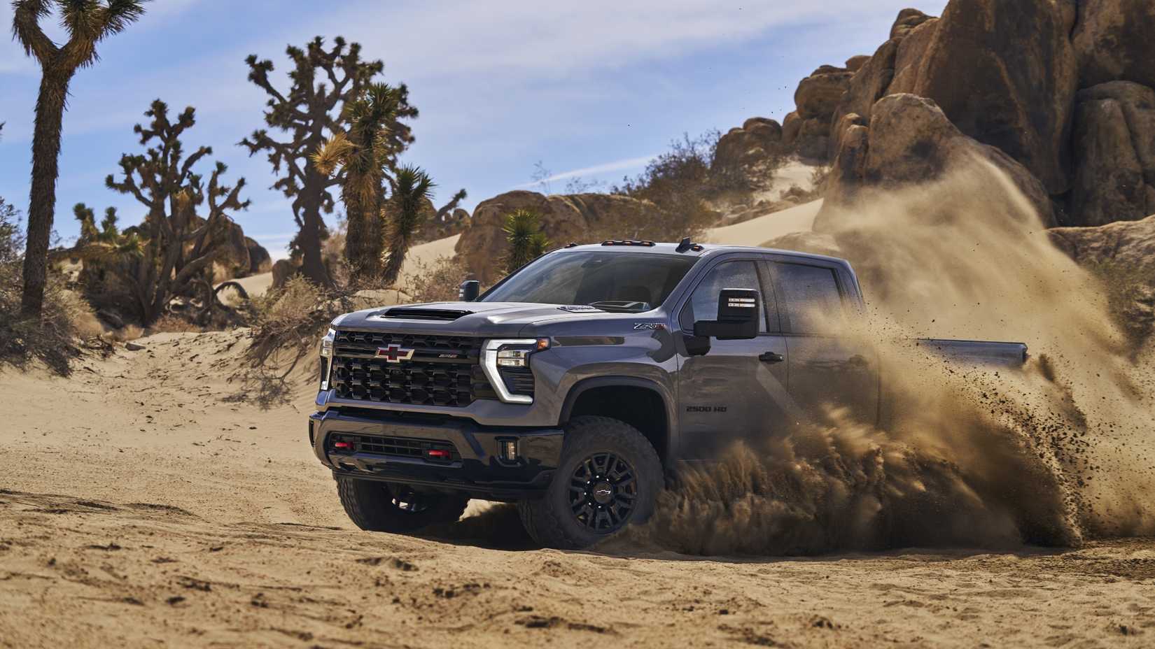 Front 3/4 action shot of a 2024 Chevrolet Silverado HD ZR2 drifting through sand