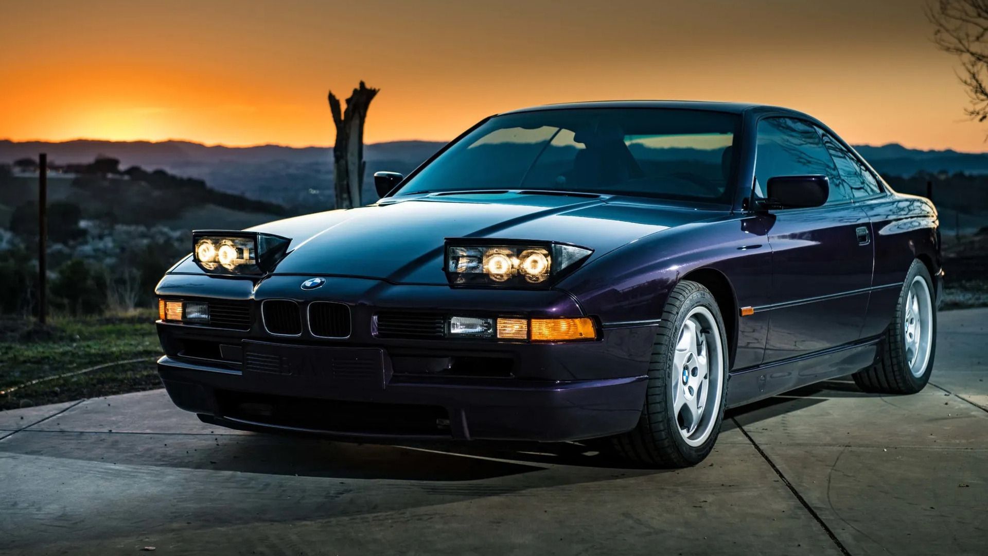 BMW 850 CSi roxo 1995 com luzes abertas, estacionado, vista frontal 3/4