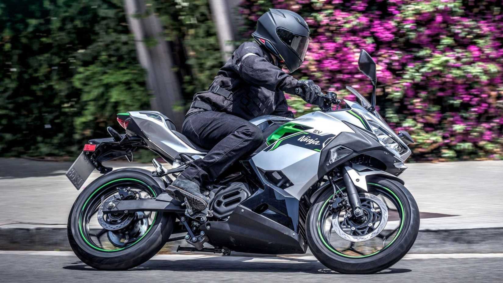 Side profile action shot of 2024 Kawasaki Ninja E-1 electric sports bike taking a turn in city road.